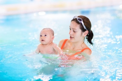 Young Mother And Her Newborn Baby Having Fun In A Swimming Pool