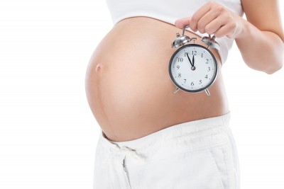 Pregnant woman's belly with an alarm clock