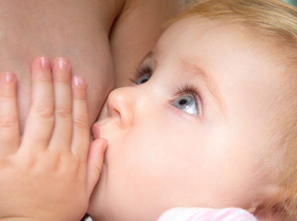 little baby sucking breast mother with open eyes