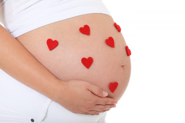 Pregnant woman with several red hearts on her baby bump. All on